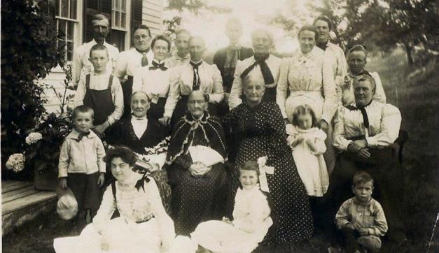 Circa 1900: left side front to back is Russell, Paul Murray, and Edwin Yeaton. Next row is Carrie (sitting), Lydia Ann (wife of Paul Yeaton, Jr.), and Lillian, with the bow. Next to Lydia is her sister, Eliza (wife of Andrew ). Girl in front with the bow in her hair is Donna Yeaton. The lady to the right of Eliza may be her daughter Mary.